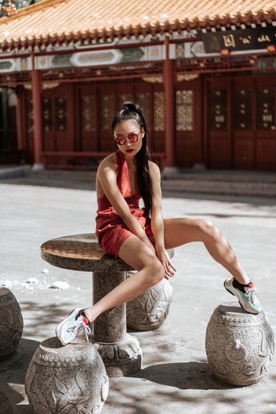 穿着红色吊带裙坐在圆石桌上的女人